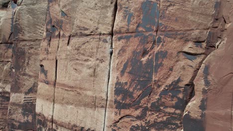 aerial view of man climbing on steep vertical cliff