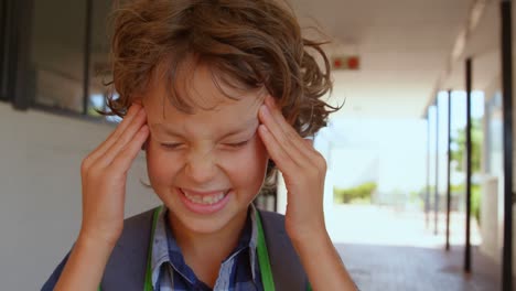 Vista-Frontal-De-Un-Colegial-Caucásico-Irritado-Parado-En-El-Pasillo-De-La-Escuela-4k