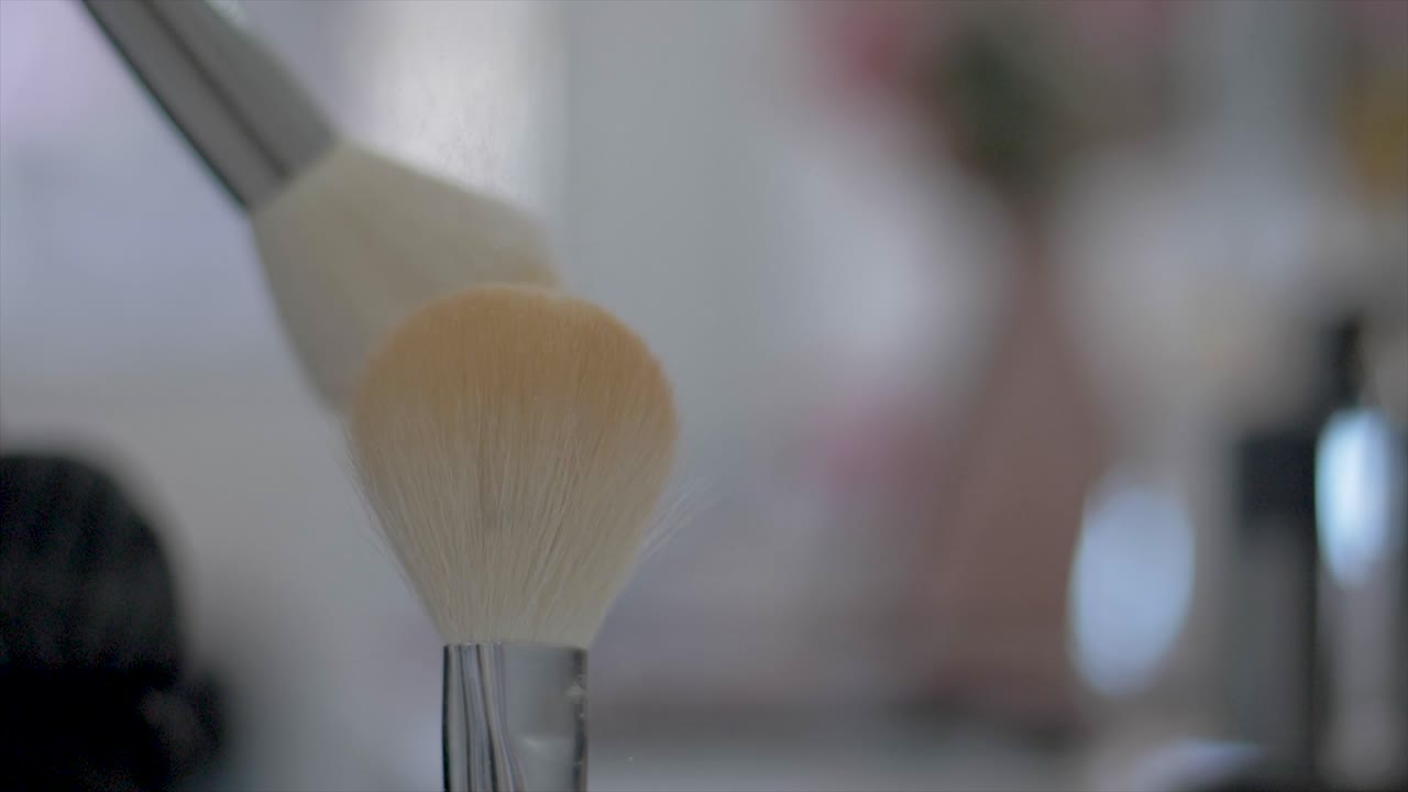 여성의 손에 있는 슬로우 모션 가루 먼지와 브러시