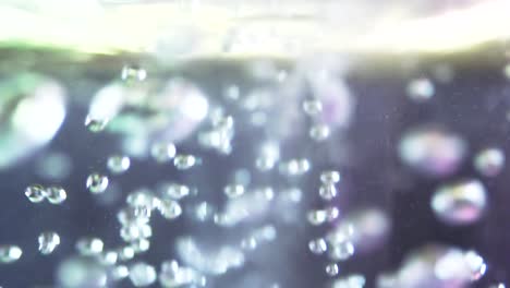 un primer plano extremo y una toma en cámara lenta extrema de una bomba de baño rosa acercándose a la superficie del agua