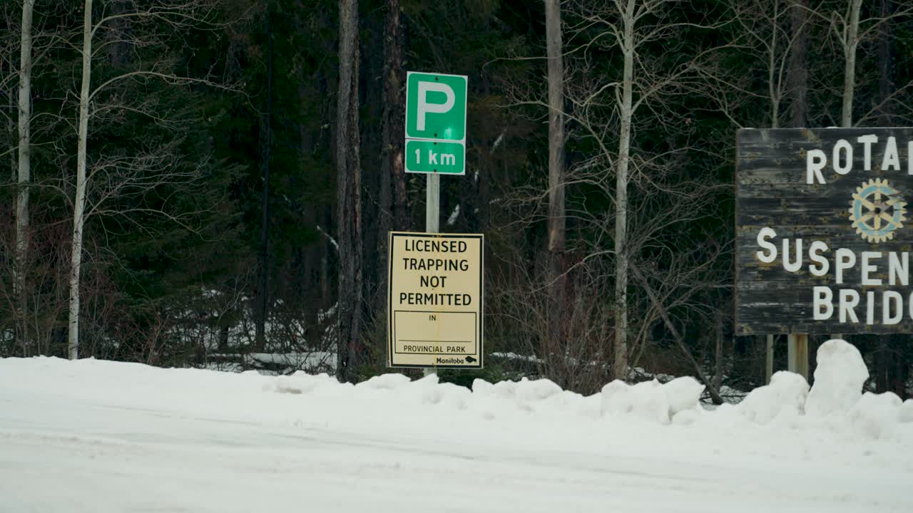 A Group of Entry Signs for No Licensed Trapping Permitted Rotary Suspension Bridge Pisew Falls Travel Manitoba Winter Forest Provincial Park near Artic Northern Thompson Canada