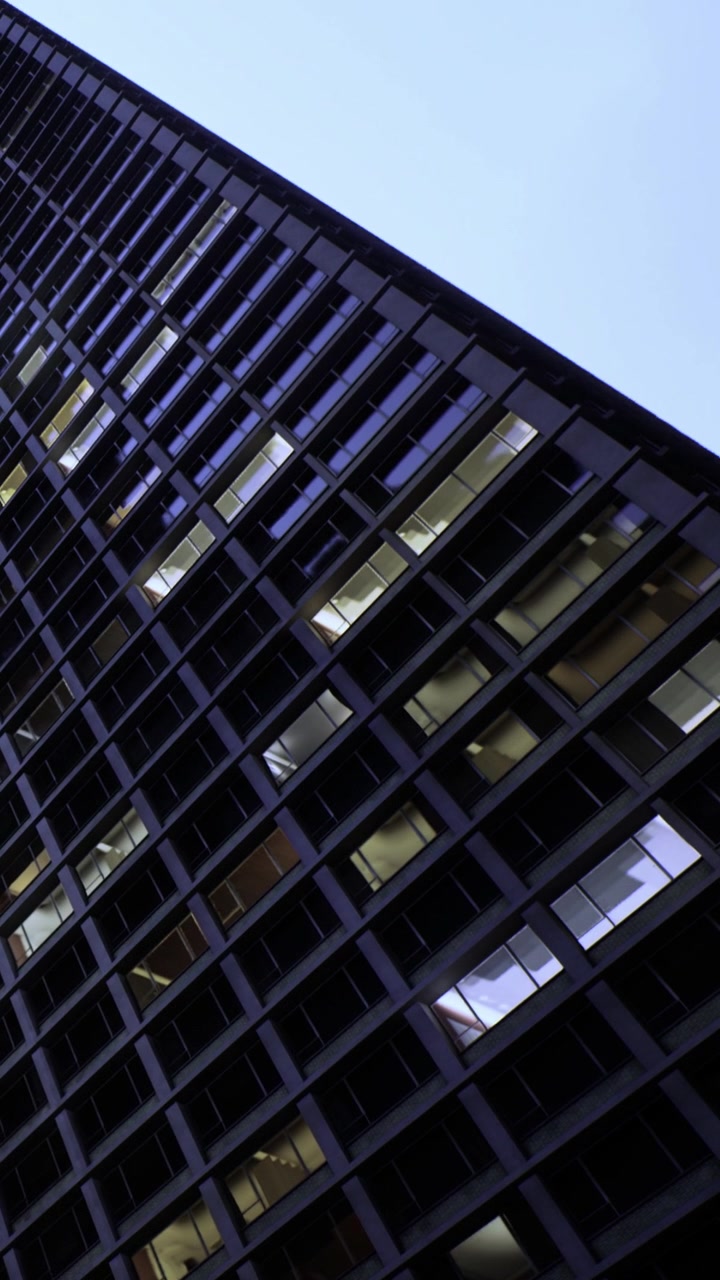 Estructura de edificio moderno al anochecer con ventanas anguladas que muestran luz