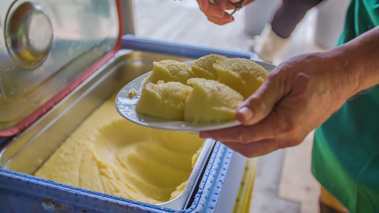Movimento rallentato di un uomo che serve polenta di mais su un piatto durante un pranzo tradizionale su zattera