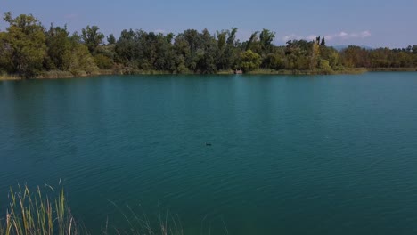 aerial view over a beautiful landscape with a natural lake, its calm turquoise water surrounded by wild vegetation, in the spanish mountains