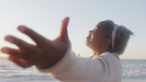 Happy-senior-african-american-woman-widening-arms-at-beach,-in-slow-motion