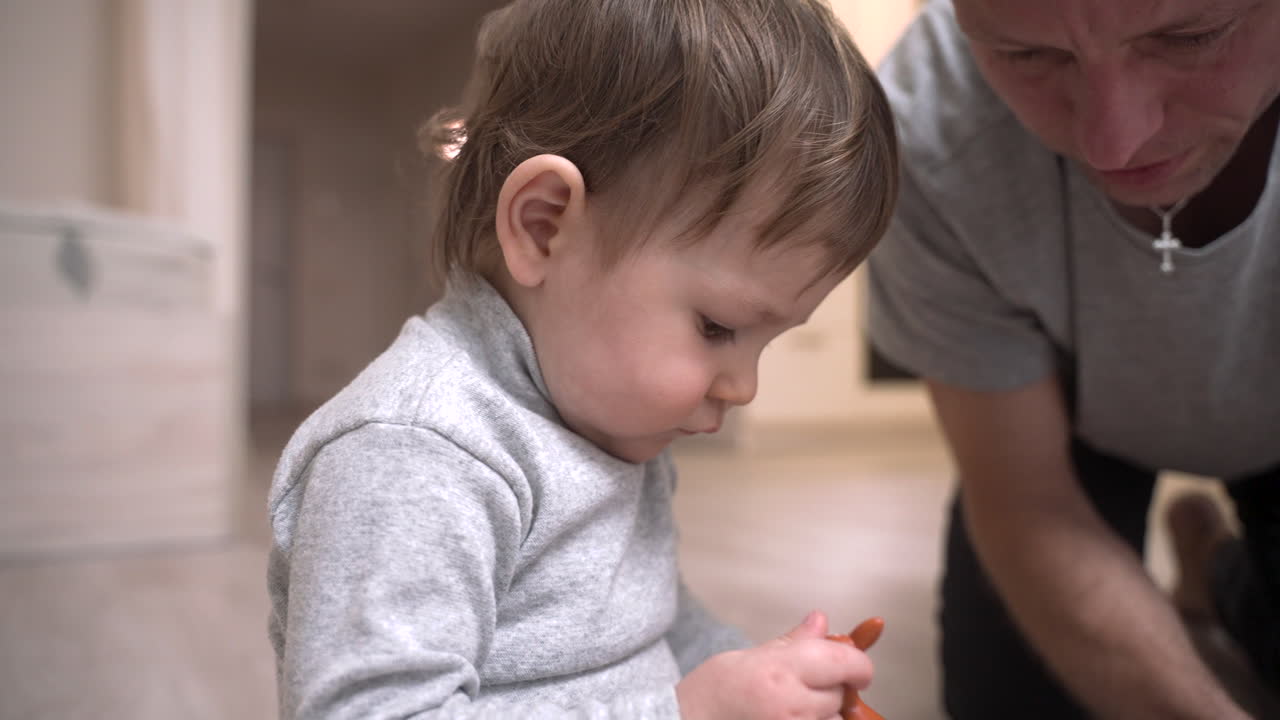 Baby And Father Sitting On The Floor In The Living Room While Playing With Toys 1