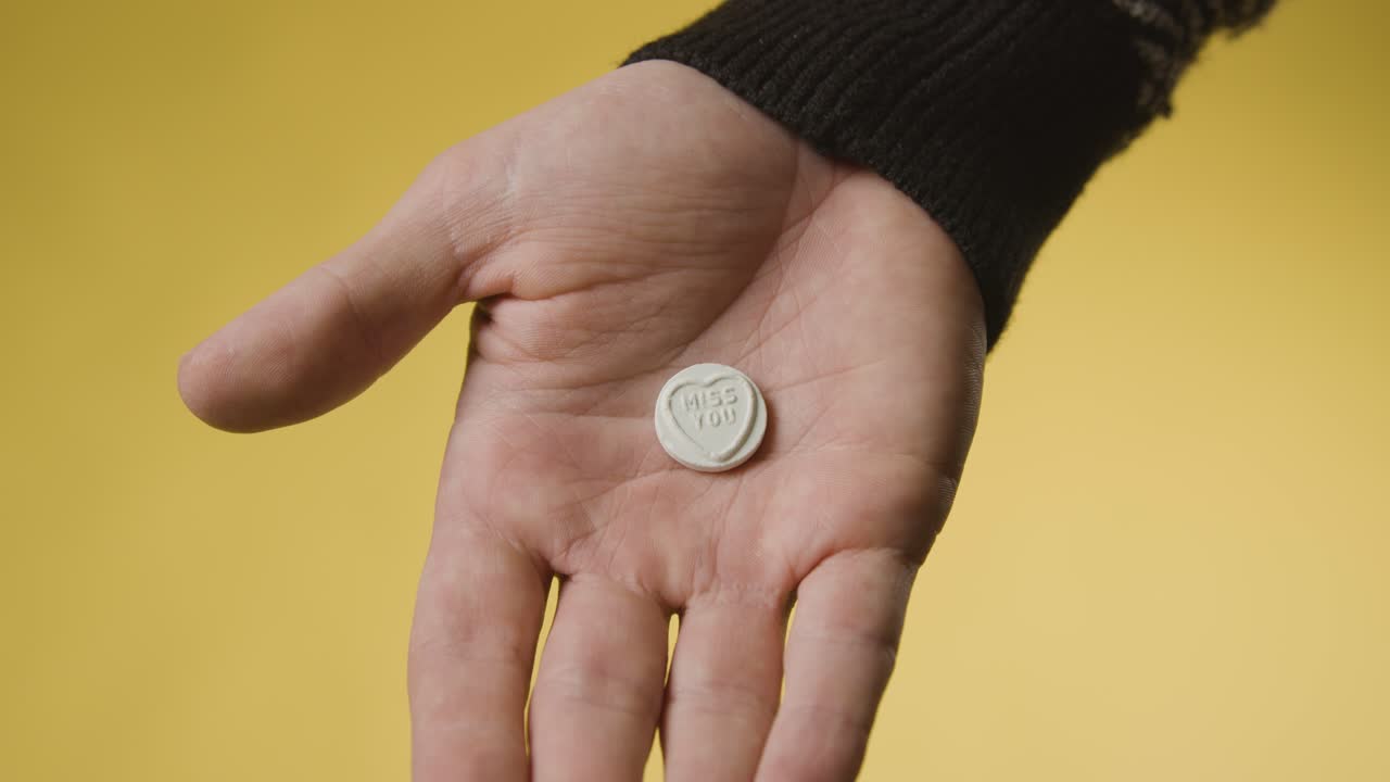 노란색 배경에 당신이 그리워요 메시지와 함께 심장 사탕을 들고 손을 닫습니다