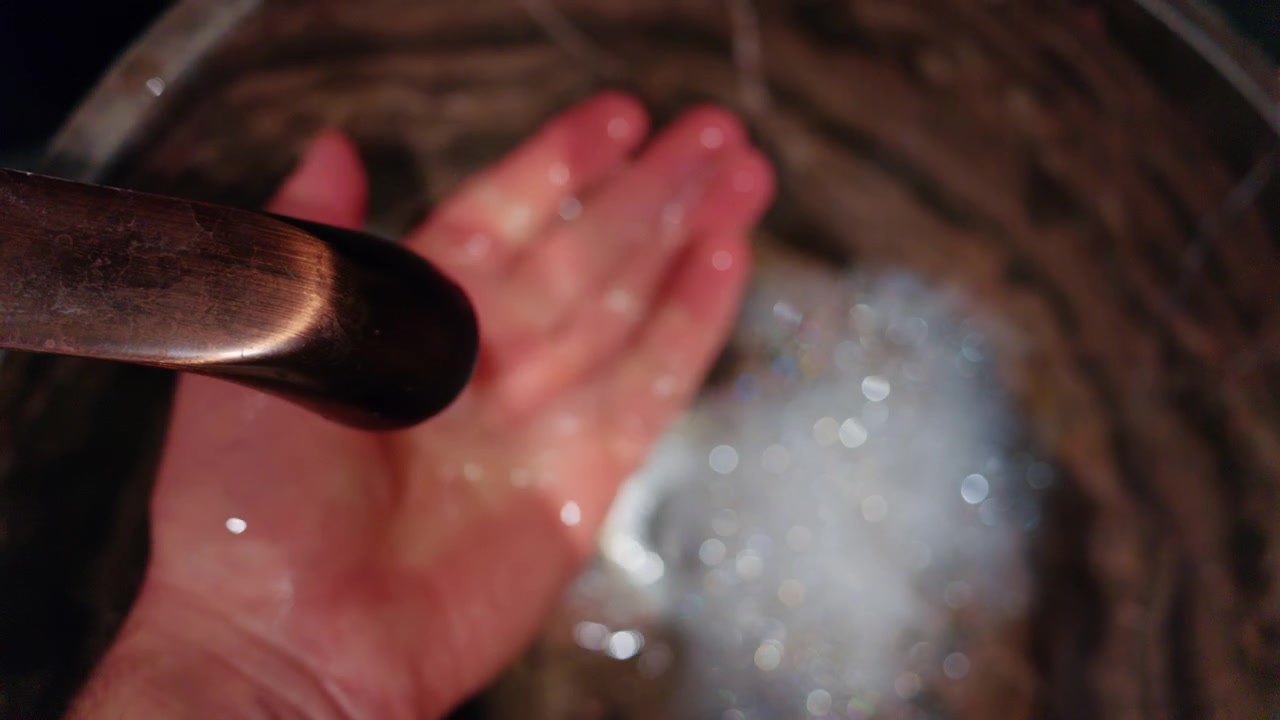 Una persona si lava le mani con il sapone sotto l'acqua corrente in un lavandino.