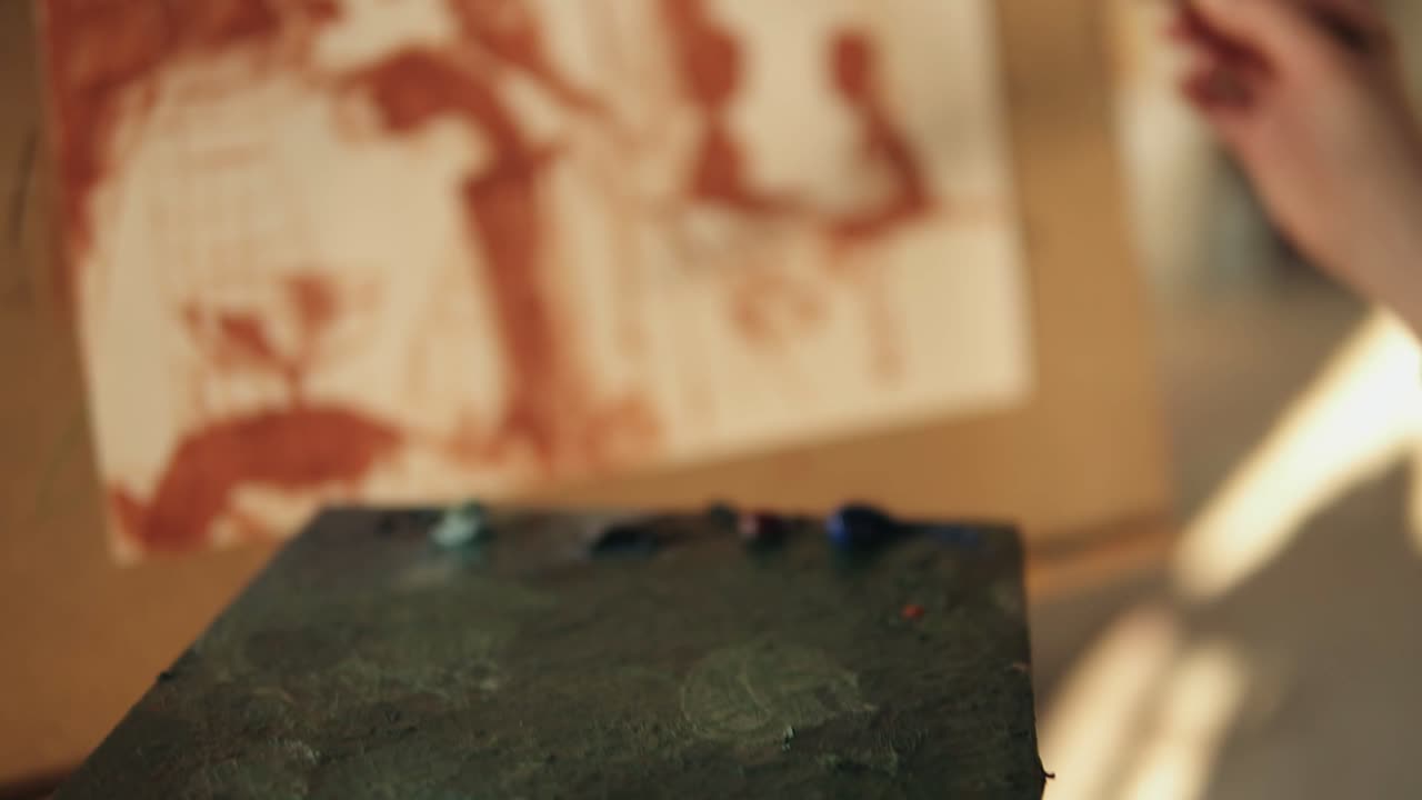 cierre las imágenes en cámara lenta de la mano del artista cuidada con precisión esparciendo pintura al óleo en la paleta y agregando más color a la pintura en el caballete