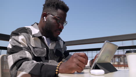 man using tablet at outdoor cafe