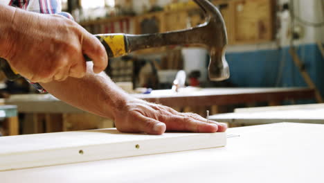 focus on carpenter hammering in wood plank