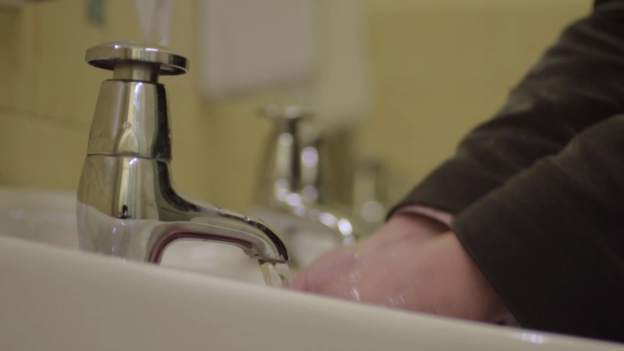 lavarse las manos en un lavabo público con dispensador de jabón