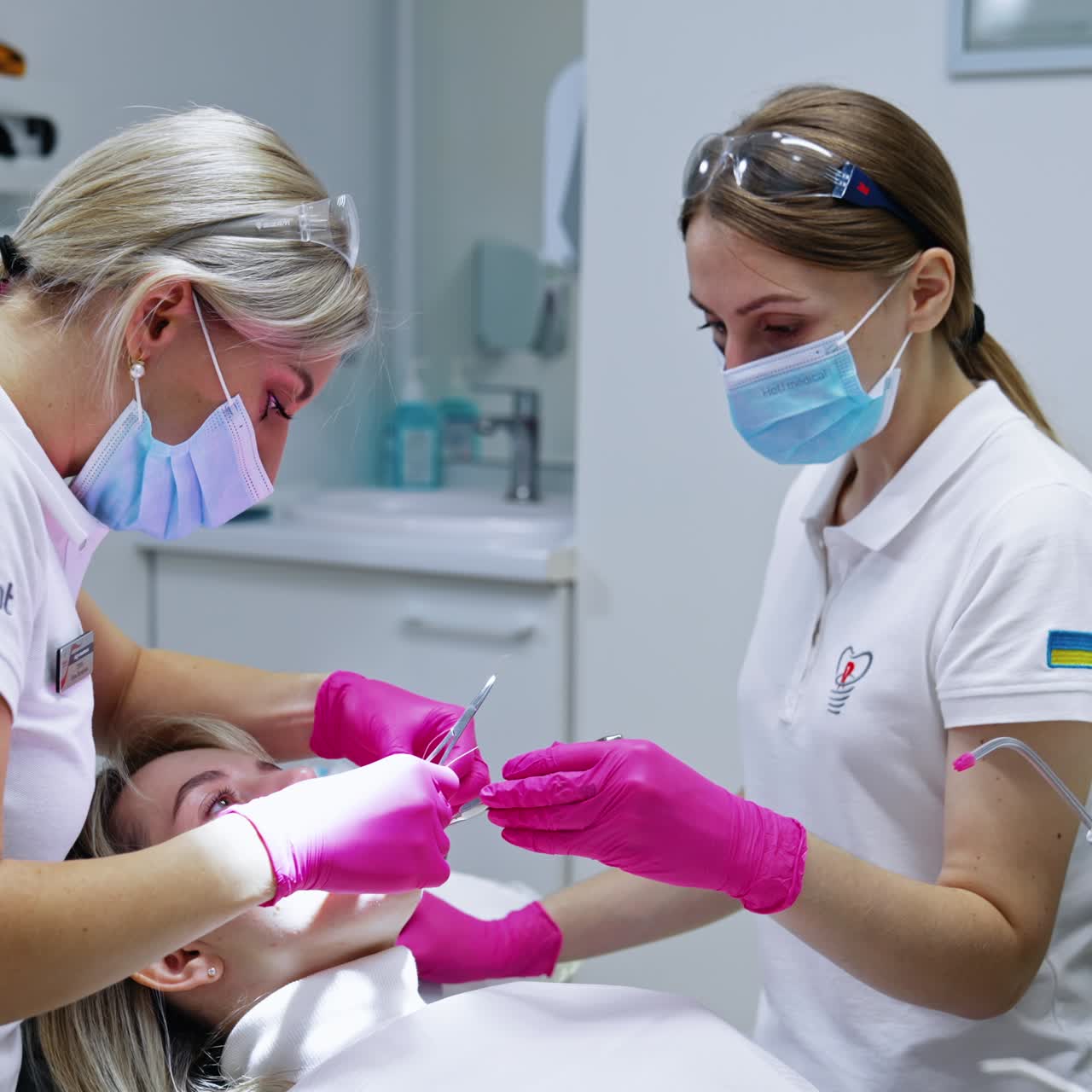 Dentist using scissors providing dental care for the patient. Female nurse holding the instrument in woman's mouth