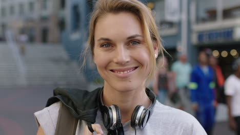 portrait of independent blonde woman smiling happy optimistic wearing headphones urban city sidewalk