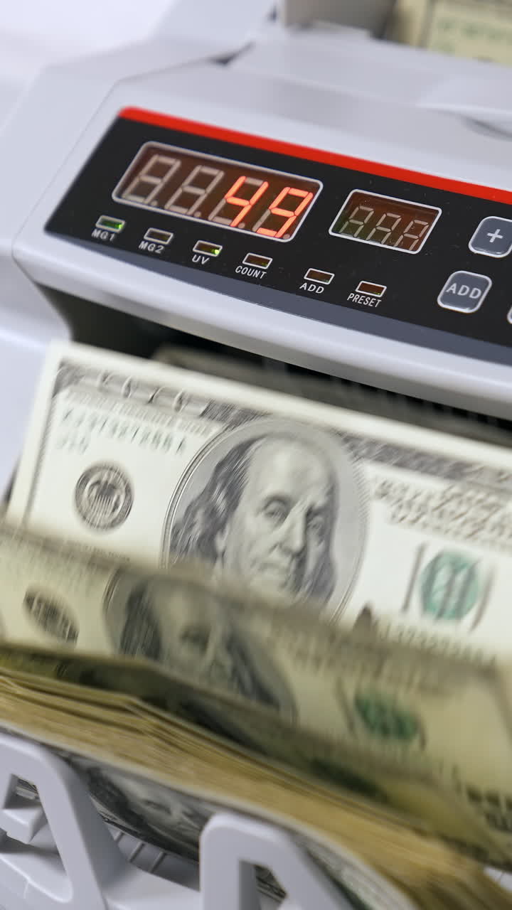Money counting equipment for paper money calculation. Woman puts a pack of dollar banknotes to count. Automatic mechanism for bank financial operations. Vertical video