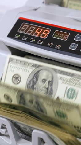 money counting equipment for paper money calculation. woman puts a pack of dollar banknotes to count. automatic mechanism for bank financial operations. vertical video