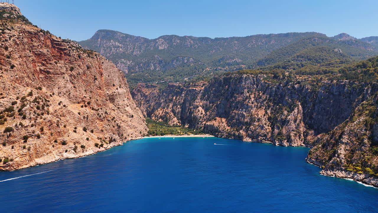 Stunning blue waterscape of the Mediterranean Sea surrounded by the rocks. Yachts move by the seascape. Turkey nature. Aerial view