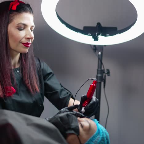cosmetologist work with patient. the cosmetologist makes a tattoo of the eyebrows of the patient