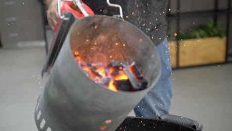 Flaming-coals-are-added-to-charcoal-grill,-slow-motion