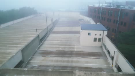 aerial descending dolly along parking garage ramp leading to upper level on foggy misty morning