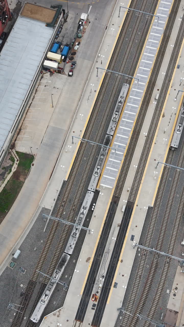 Vertical drone shot rotating above a train approaching the station, in Denver