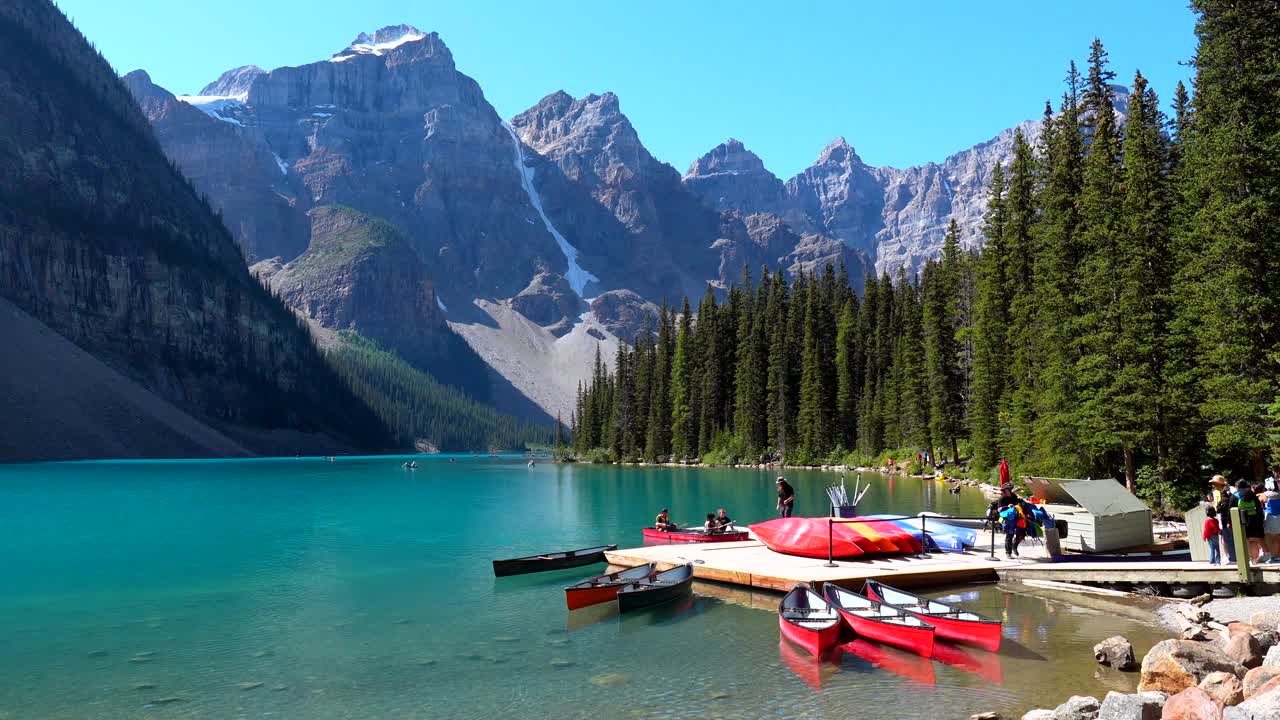 Naturskøn udsigt over Moraine Lake med kanoer og bjerge