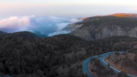 aerial shot flying over the cloudy mountain range of mount olympus with roadway