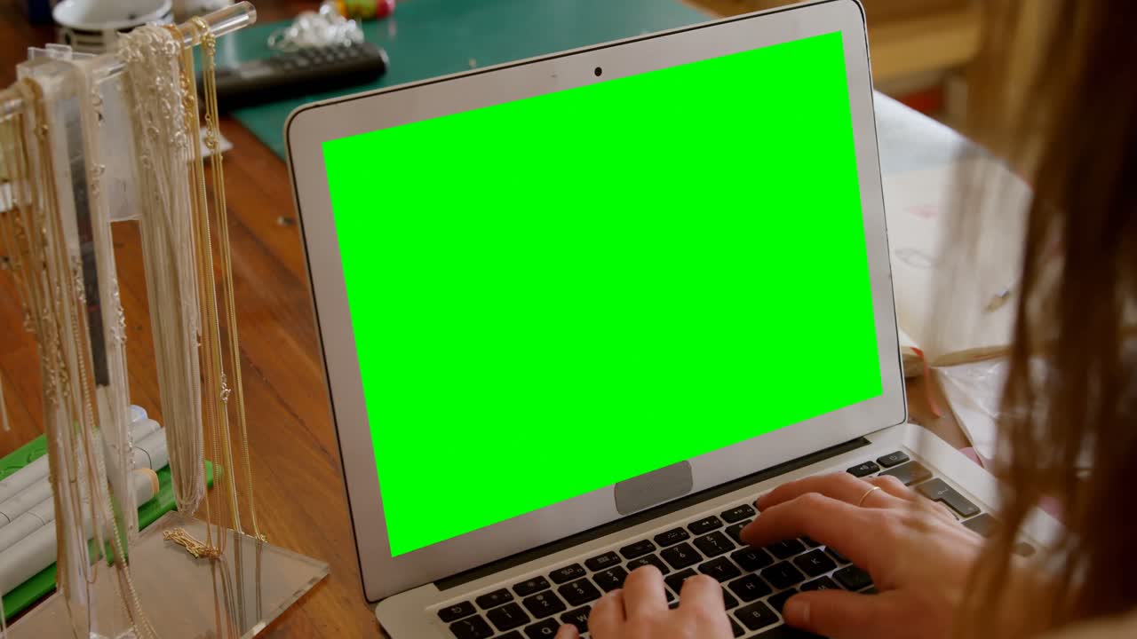 diseñadora de joyas usando una computadora portátil en el taller 4k