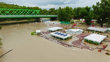 aerial view of extensive flooding in bratislava, showcasing the overflowing danube river, submerged trees, and affected infrastructure. the city landscape and iconic landmarks are visible.