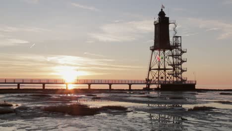 hermoso faro antiguo al atardecer en el mar del norte mientras la marea baja