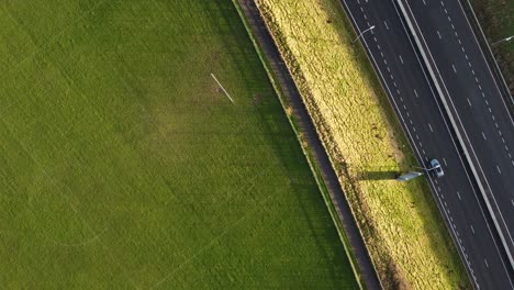 Statischer-Overhead-Drohneclip-Eines-Fußballfeldes,-Das-Auf-Eine-Autobahn-Trifft,-Die-Durch-Einen-Pfad-In-Manchester,-Großbritannien,-Getrennt-Ist