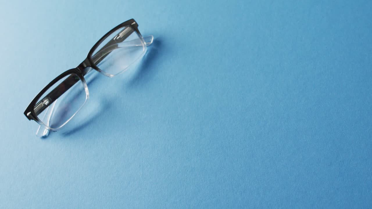Video of pair of glasses on blue background with copy space