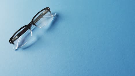 video of pair of glasses on blue background with copy space