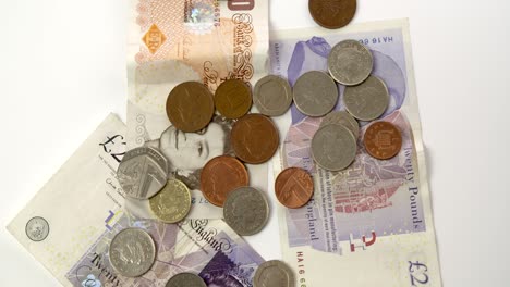 pound coins and notes rotating on white background