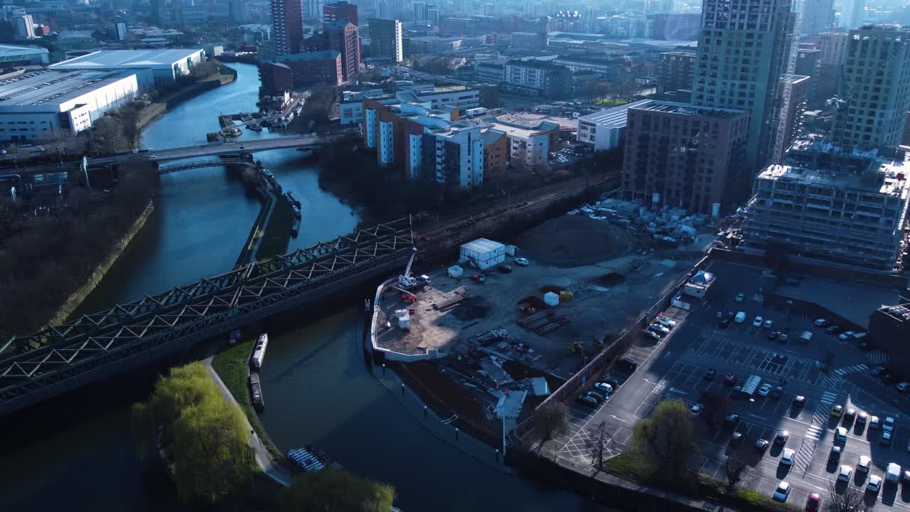 Cantiere di un grattacielo a East London, visto dall'alto, vicino a un canale e a un ponte ferroviario in un tardo pomeriggio invernale. Tracciato in avanti.