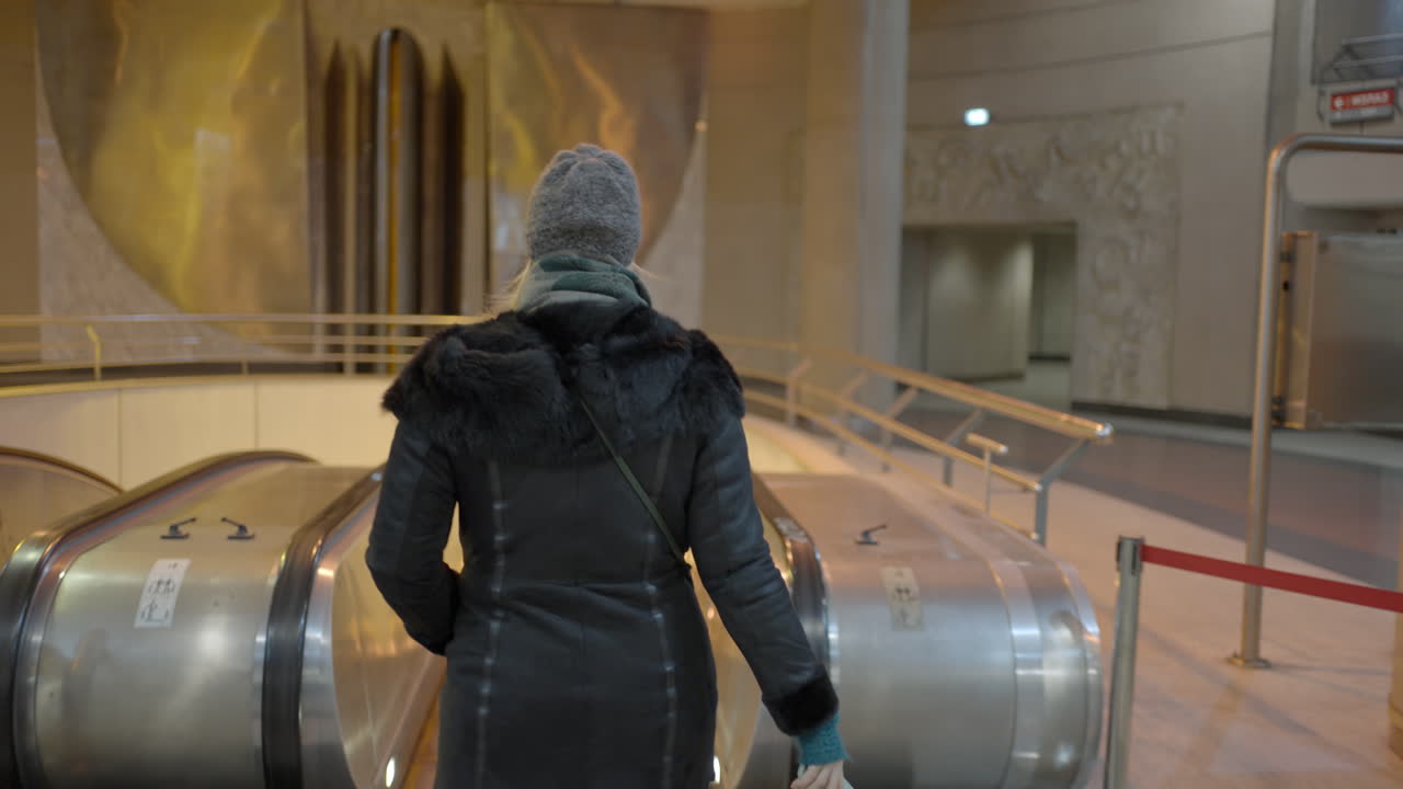mujer en la escalera mecánica en la estación de metro