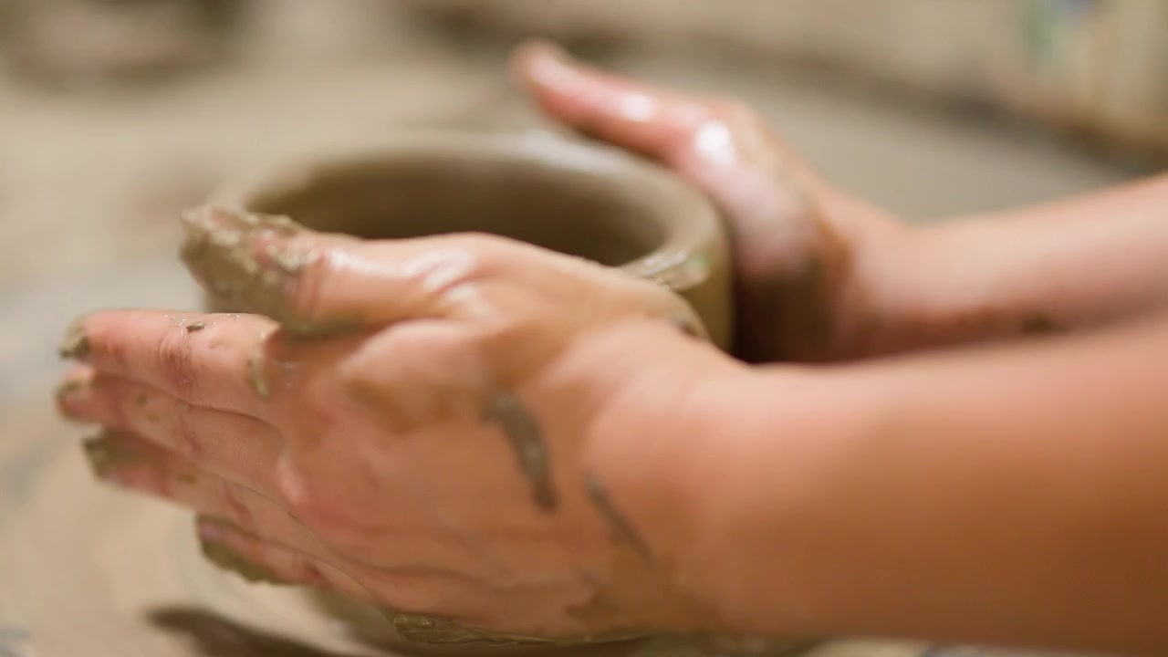 Primo piano delle mani di un vasaio che modellano un vaso di ceramica su un tornio a Nonthaburi.