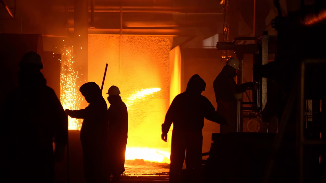 Operai caucasici della fonderia in silhouette vicino a un forno fusorio, turno di notte in acciaieria con scintille, lavoro pesante