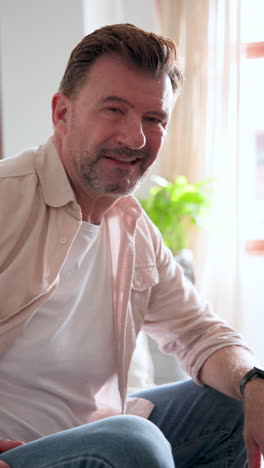 vertical video: relaxing at home, senior man smiling during christmas season with decorations