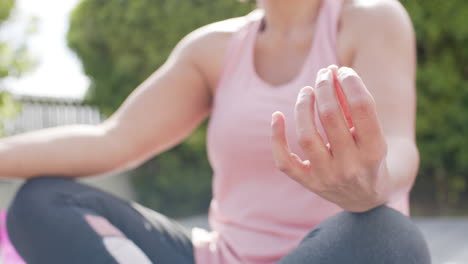 Mujer-Mayor-Birracial-Practicando-Yoga-En-Un-Jardín-Soleado,-Cámara-Lenta