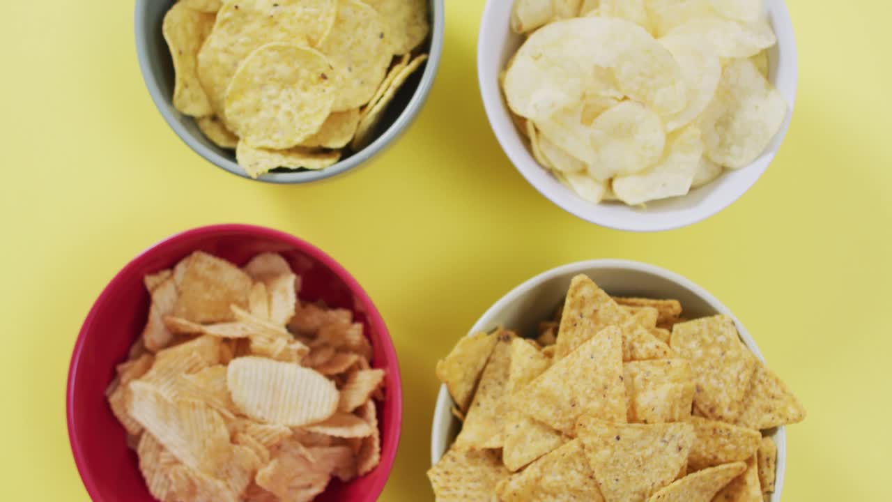 cerrar cuatro cuencos llenos de una variedad de papas fritas con espacio de copia en la superficie amarilla