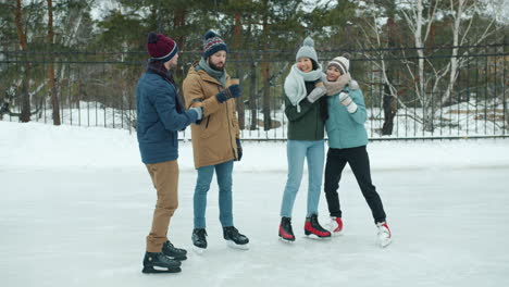 friends ice skating and enjoying coffee in winter park