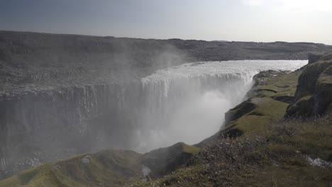 Toma-Panorámica-De-La-Cascada-De-Dettifoss-Con-Niebla-Que-Se-Eleva-Con-El-Viento-A-Través-Del-Valle.