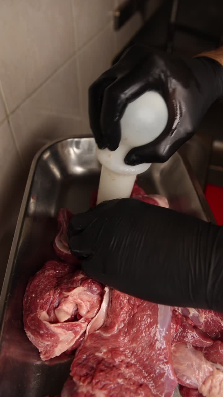 Hands Pushing Raw Meat into a Meat Grinder