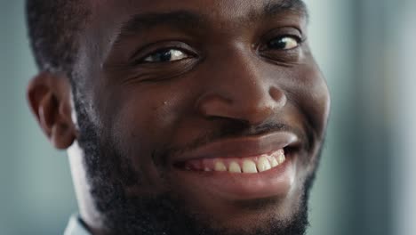 close up portrait of a black african american handsome male in a light blue casual shirt. successful man calmly smiles while looking at camera. happy stylish businessman or a doctor in hospital.