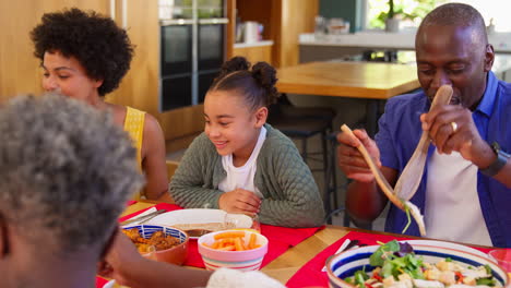 Familie-Mit-Mehreren-Generationen,-Die-Zu-Hause-Am-Tisch-Sitzt-Und-Gemeinsam-Essen-Genießt