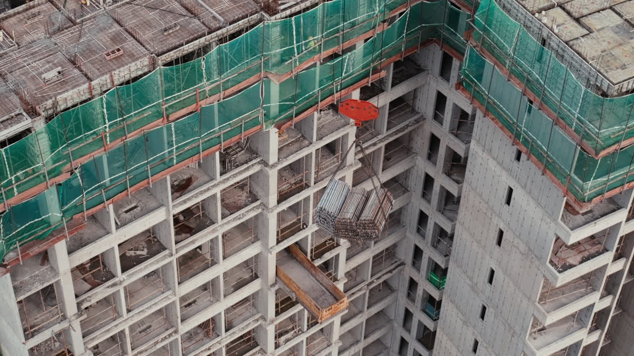 Edificio de gran altura en construcción en Bangkok, Tailandia, con estructura de hormigón expuesto, andamios y grúa elevando materiales. Escena de desarrollo urbano que muestra el crecimiento inmobiliario y la infraestructura