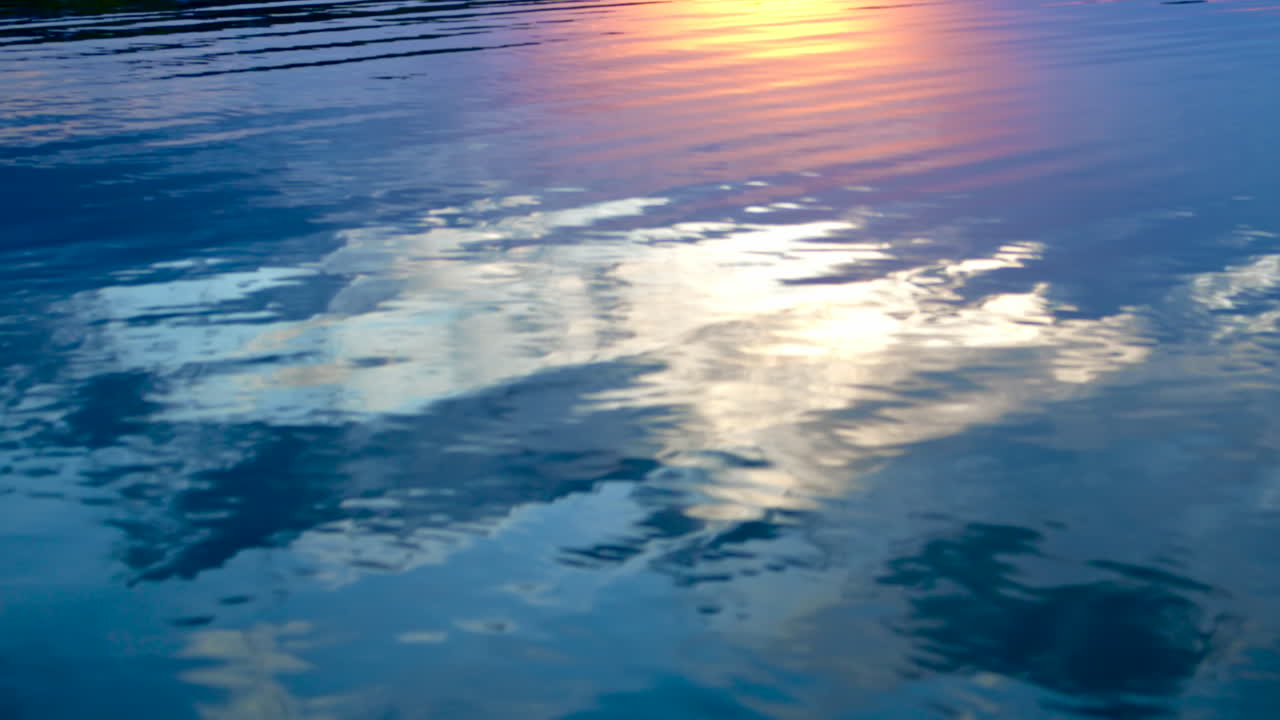 View of a water surface with blue sky and sun reflected in it