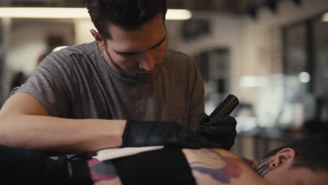 caucasian man tattooing woman at the studio.