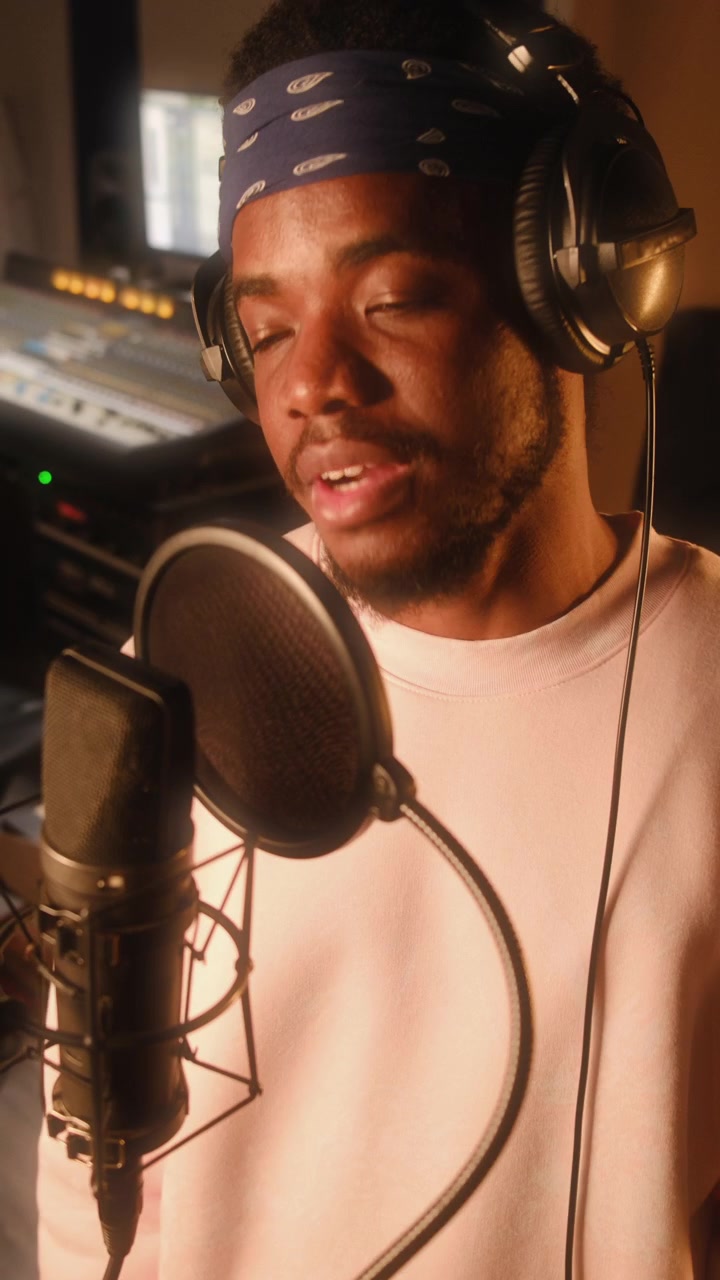 Giovane cantante afroamericano che si esibisce al microfono in uno studio di registrazione